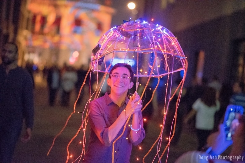 person holding lit up umbrella at night
